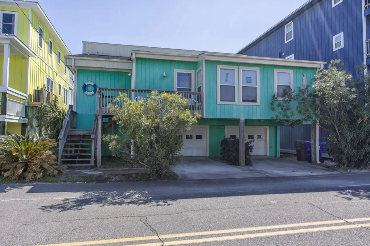 This image displays the brightly painted exterior of the house, with entrance steps leading up and lush green foliage surrounding the property. The inviting porch hints at outdoor relaxation and group gatherings, conveying the welcoming atmosphere of Miller’s Whimsy before even stepping inside.